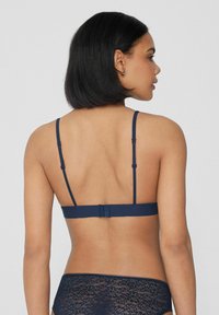 Granatowy biustonosz z cienkimi, regulowanymi ramiączkami i zapięciem na haftki. Wykonany z gładkiego materiału, o minimalistycznym designie, bez ozdób.