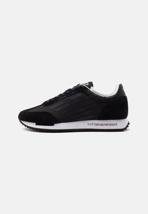 Pantof sport negru cu talpă joasă, panouri texturate, talpă intermediară albă și logo „EA7 Emporio Armani” pe talpa laterală, afișat pe un fundal alb.