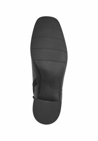 Suela de zapato negra con una textura suave, con ranuras horizontales para mayor agarre y con una cremallera lateral. Tamaño marcado como 37.