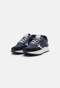 Tumesinine suede ja võrgusneakerid valgete aktsentidega, sidumisdisain, pehmendusega krae, tekstuuriga talla ja logo keelel.