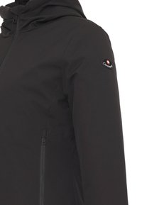Giacca softshell nera con zip, cappuccio e patch del logo sulla manica. Il tessuto ha una texture liscia ed è aderente.