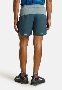 Men's running shorts in teal, featuring an elastic waistband with a gray back panel. Includes reflective accents and split side seams.