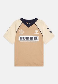 Beige och tan t-shirt med kortärmar och mörkblå V-ringning, med "HUMMEL" logotyp och text på framsidan, samt tre ränder på ärmarna.