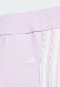 Jasnofioletowe spodnie dresowe z białym wzorem w trzy paski, teksturowaną tkaniną oraz detalami z logo Adidas i Disney na nogawce.