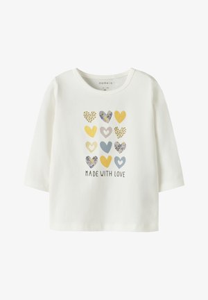 Camisa blanca de manga larga con un patrón de corazones en varios colores y texturas, con el texto "HECHO CON AMOR" en la parte inferior.