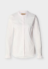 Blouse blanche à manches longues avec col rond, boutons dissimulés à l'avant, poignets volantés et ourlet droit, présentée sur un fond uni.