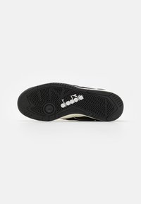 Black athletic shoe sole with rubber material, textured tread pattern, and white logo accent. Features a rounded edge and durable design.