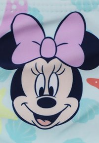 Grafica di Minnie Mouse con contorno nero, fiocco rosa e caratteristiche facciali vivaci su uno sfondo azzurro chiaro con accenti colorati.