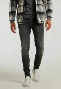 Gray denim jeans with a slim fit, featuring a faded texture. Worn with a black sweater and a white and gray plaid flannel jacket. White sneakers.