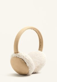 Umelé shearlingové ušné poháriky v bielej a béžovej farbe, s polstrovaným béžovým hlavovým mostíkom, navrhnuté pre teplo a pohodlie. Mäkká textúra a zaoblený tvar.
