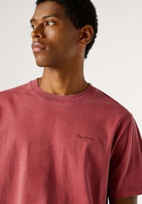 Rood katoenen T-shirt met een ronde hals, voorzien van een klein, donker logo op de linkerborst en een ontspannen pasvorm, met een zachte, gestructureerde uitstraling.