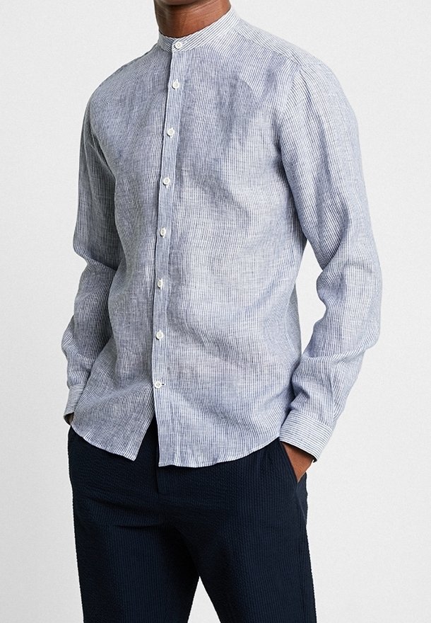 Camicia a maniche lunghe a righe blu e bianche con colletto alla mandarino, caratterizzata da bottoni bianchi e un tessuto morbido e testurizzato.