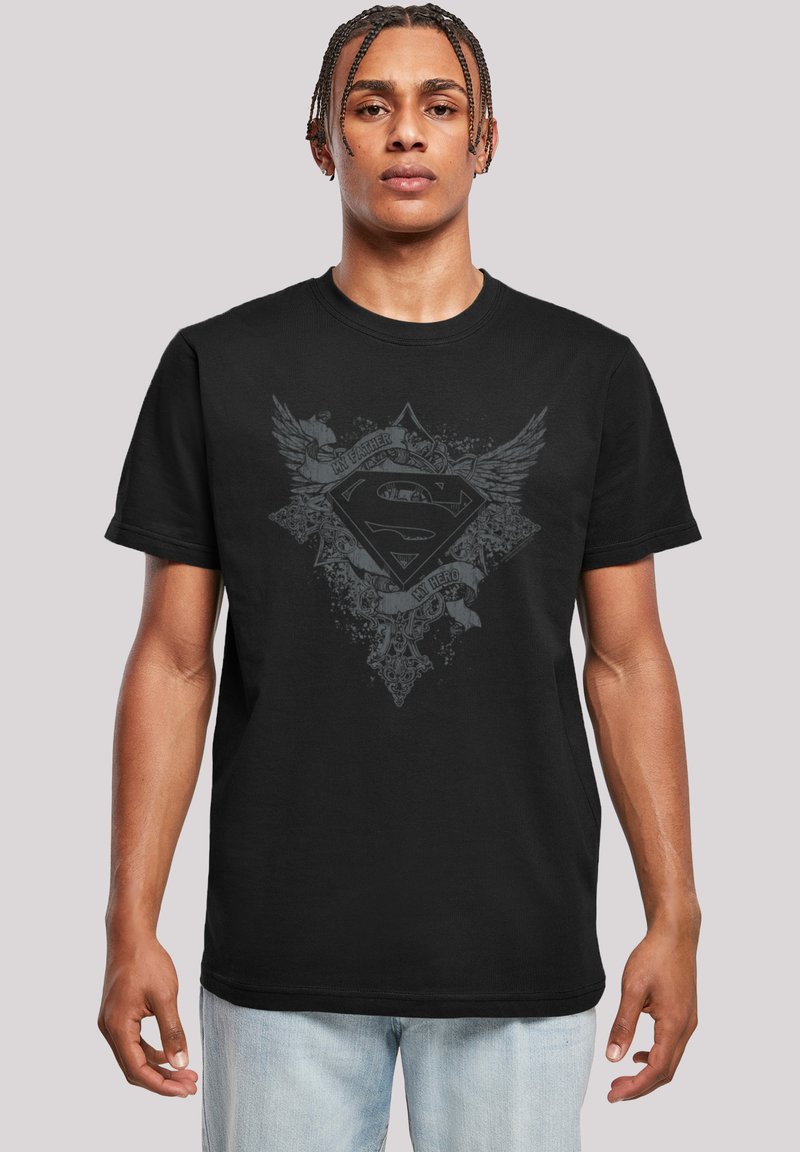 Black cotton T-shirt featuring a Superman logo with wings, detailed patterns, and the text "My Father, My Hero." Short sleeves and round neck.