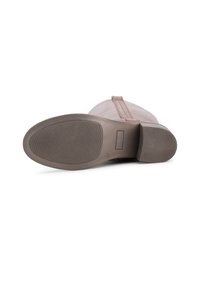 Botte en cuir marron avec une texture lisse, bout rond et semelle en caoutchouc dotée de stries horizontales pour une meilleure adhérence.