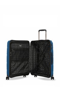 Valigia rigida blu con scomparti aperti, interno nero a motivo, cinghie incrociate, tasche con zip e manico telescopico estensibile su ruote.