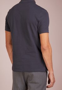Polo shirt navy à manches courtes, avec col côtelé et fentes sur les côtés. Confectionné en tissu texturé, avec un détail au niveau de l'encolure au dos.