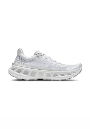 Scarpa da ginnastica bianca con suola spessa e ventilata, tomaia in mesh, design con lacci e motivo sottile vicino al tallone, vista di profilo su sfondo bianco.