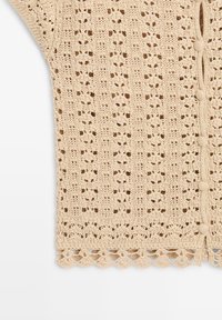 Tissu beige crocheté avec des motifs floraux et géométriques en ajourage, boutons ronds recouverts de tissu et détail de bord festonné.