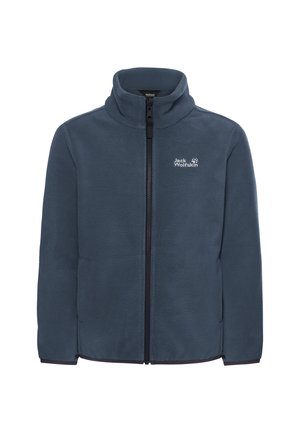 Kind mit lockigem Haar, trägt eine dunkelgraue Fleecejacke mit Reißverschluss über einem rosa Shirt und schwarzen Cargohosen, steht mit einer Hand in der Tasche.