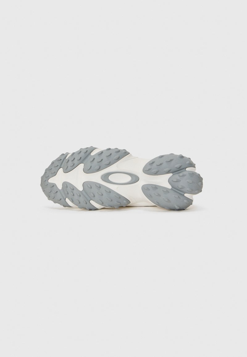 Shoe outsole with a wavy, textured gray rubber surface and a white base. Features rounded edges and a logo in the center.