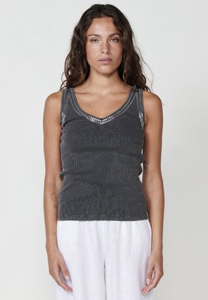 Haut sans manches gris avec un décolleté en V, présentant un tissu texturé et des perles décoratives le long du décolleté. Design ajusté.