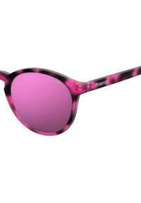 Lunettes de soleil écaille de tortue rose avec des verres dégradés roses. Forme ronde, matériau en plastique léger, portant la marque "Polaroid" sur la branche.