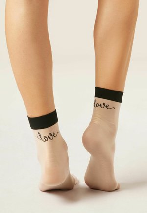 Kotníkové průsvitné ponožky s černými lemy a slovem "love" vyšitým černě na zadní straně obou nohou.