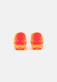 Lyst orange fodboldstøvler med et elegant design, der har tekstureret syntetisk materiale og røde detaljer, herunder logo og brand-elementer.