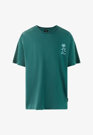 Grøn bomulds t-shirt med korte ærmer. Har en lille hvid palmetræ-logo på venstre bryst og en label i siden. Blød tekstur.