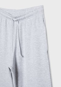 Lichtgrijze sweatpants met een elastische tailleband en trekkoord. Zachte stoftextuur en zijzakken zijn in het ontwerp verwerkt.