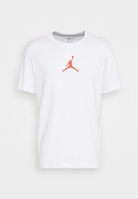 Vit kortärmad t-shirt med rund halsringning med en röd siluett av en basketspelare som hoppar och håller en boll på bröstet.