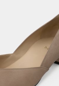Chaussure pour femme en daim beige à petit talon, avec un bout arrondi et une doublure intérieure lisse, sur un fond blanc.