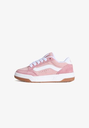 Le sneakers in suede rosa presentano una striscia laterale bianca, lacci bianchi e una suola in gomma color caucciù, con fori sulla punta per la traspirabilità.