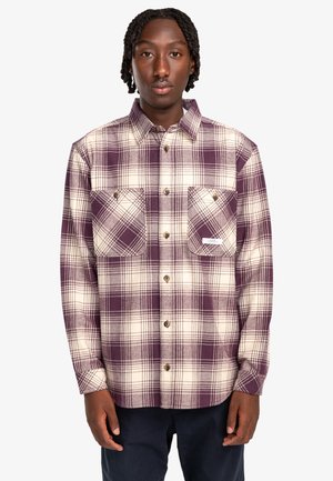 Purple and cream plaid flannel shirt with two chest pockets and brown buttons. Buttoned collar and relaxed fit. Soft, textured fabric.