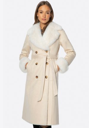 Beige dubbelzijdig jassen met een grote witte bontkraag en manchet, ceintuur in de taille, met zijzakken en ronde bronzen knopen.