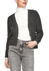 Donkergrijze geribbelde cardigan met een ronde halslijn, knopen aan de voorkant en lange mouwen, gedragen over een witte turtleneck en grijze jeans.