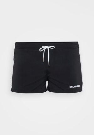 Pantalones de baño para hombres negros con rayas laterales blancas, cordón blanco en la cintura y logo "DSQUARED2" en la pierna izquierda.