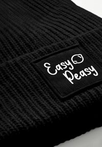 Black ribbed beanie with a rectangular patch. The patch features white text reading "Easy Peasy" on a textured black background.