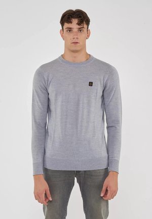 Maglione lavorato a maglia di colore grigio chiaro con maniche lunghe e scollo rotondo. Presenta una piccola targhetta con logo scuro sul petto. Tessuto morbido.