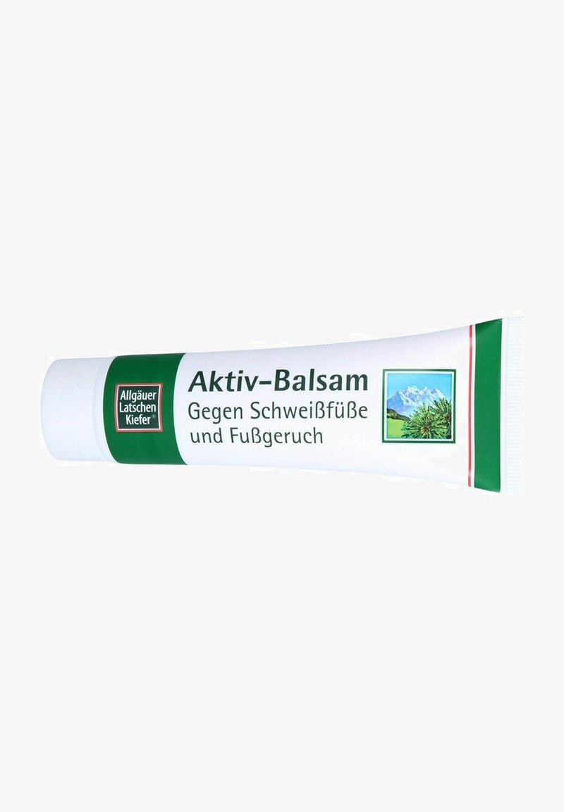 Tube Aktiv-Balsam Fußcreme mit grünem Etikett, deutscher Text über die Verringerung von schwitzenden Füßen und Fußgeruch sowie ein Bild von Bergen und Kieferzweigen.