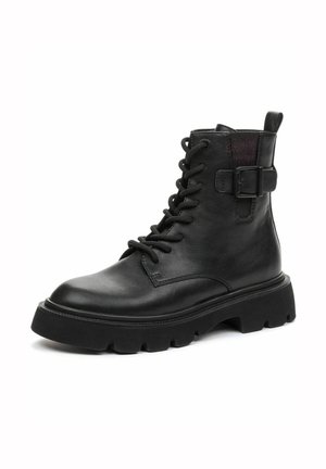 Botte de combat en cuir noir à lacets, semelle épaisse crantée et détail d’une boucle latérale, présentée légèrement en angle sur fond blanc.