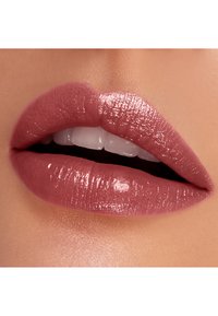 Lèvres roses nues avec une finition brillante, texture lisse et contours bien définis. Dents naturelles visibles derrière des lèvres légèrement entrouvertes.