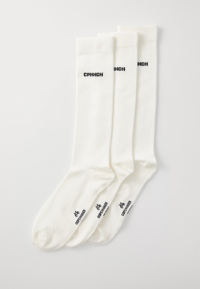 Tres pares de calcetines blancos de punto hasta la rodilla, con el texto negro "CPNHGN" en los laterales y un logo en la parte inferior.