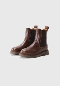 Bottines en cuir brun à chevilles avec des panneaux latéraux élastiques, bout rond et semelle en caoutchouc texturé. Équipées de languettes pour un enfilage facile.