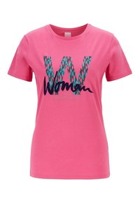 Rosa bomullströja med korta ärmar. Har ett stort, stiliserat "W" i turkos och svart text "Woman" tryckt nedanför.