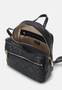 Sac à dos en similicuir noir avec garniture dorée, design matelassé et plusieurs compartiments, y compris une poche intérieure zippée.