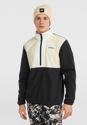 Crème en zwarte fleece pullover met een kwart rits, kenmerkend voor de textuur van de stof en het O'Neill-logo op de borst. Draagt met patroonbroek.