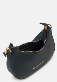 Grön läderhandväska med dragkedja, gyllene detaljer och "Valentino"-logotypen präglad på framsidan. Texturerad yta.