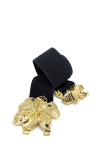 Cintura elastica nera con accenti in hardware floreale dorato su entrambe le estremità. La fibbia ha una finitura testurizzata che esalta il suo design dettagliato.