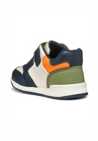 Baskets bleu marine et crème avec des accents verts et orange, en tissu texturé, et une sangle Velcro. Semelle en caoutchouc solide avec un talon légèrement surélevé.